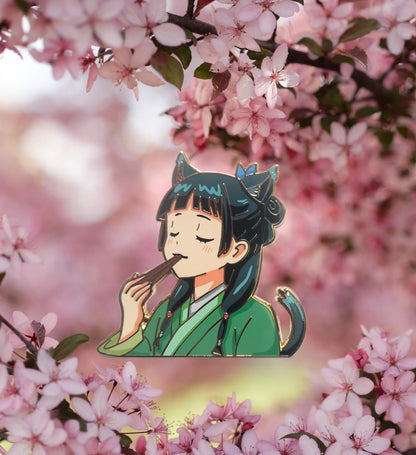 An enamel pin featuring a character, Maomao, from Apothecary diaries, depicted eating with chopsticks. Gold plating. Rubber backing. 